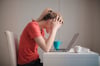 student experiencing stress with head in her hands in front of her laptop