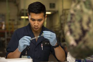 Navy Seaman Kenny Liu prepares a needle with a flu vaccination