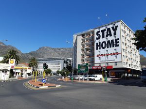 A billboard on a building in Cape Town, South Africa that reads, "Stay Home" and "If you Can" crossed out in red underneath