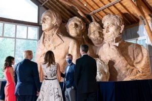 A group of people looking at an indoor version of Mount Rushmore