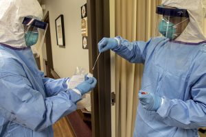 A medic with the Massachusetts National Guard takes a nasal swab that will be used to test for COVID-19 with a resident of the Life Care Center of Nashoba Valley, Littleton, Mass.