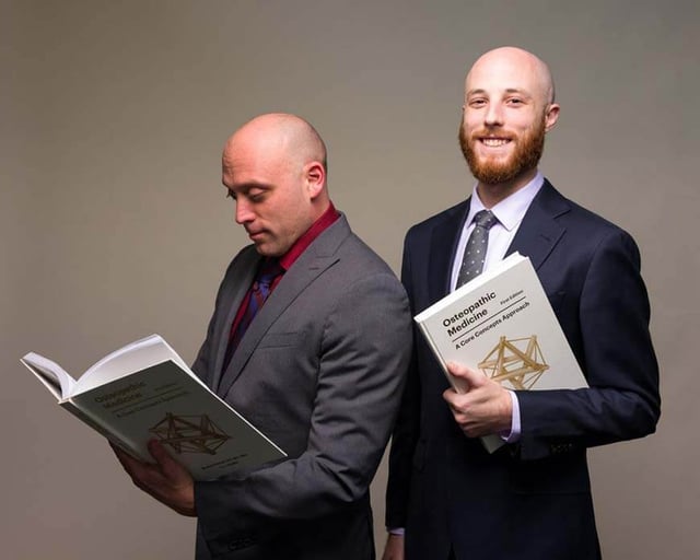 Dr. Dustyn Williams and Dr. Jeremy Polman each holding a copy of Osteopathic Medicine: A Core Concepts Approach