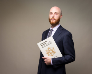 Dr. Jeremy Polman holds his new book