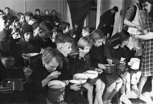 A black and white photograph of children eating rations