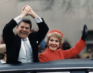 Ronald and Nancy Reagan cheering and waving from a vehicle during Ronald's inauguration