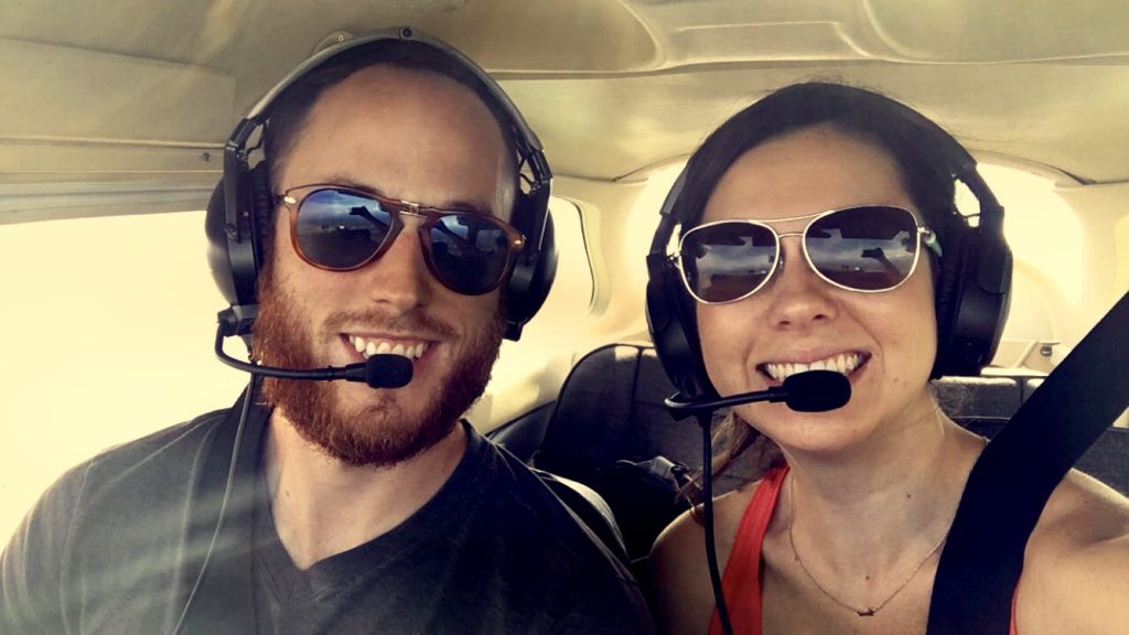 Dr. Polman and his partner in an airplane wearing headsets and sunglasses
