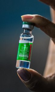 A vaccine bottle held between an index finger and thumb