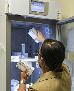A person putting vaccines in a medical refrigerator