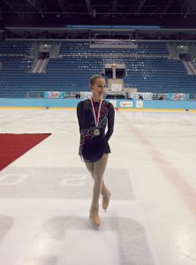Ola Kamieniecki on the ice wearing a medal