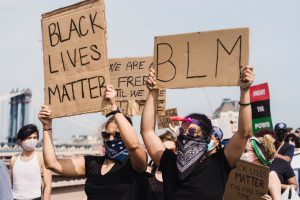 A group of protestors holding signs that read, "Black Lives Matter," and "BLM"