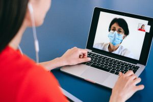 An over-the-shoulder view of a woman on a video call on her laptop