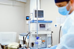 A male medical student standing in front of medical machinery