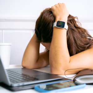 A woman holding her head at her desk