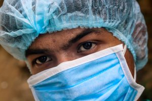 A male medical student wearing a surgeon's cap and mask