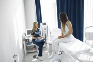 A patient sitting on a medical bed talking with the nurse