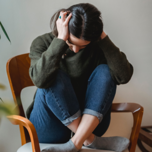 A woman in a chair holding her head