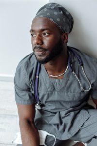 A black medical student sitting down against a wall