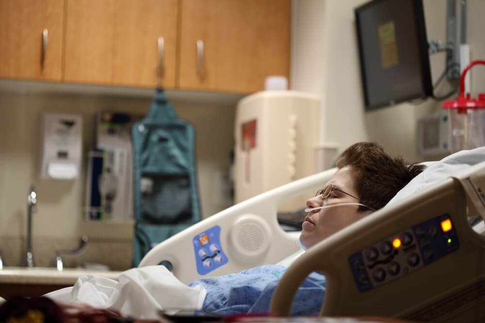 person lying on beige recliner hospital bed