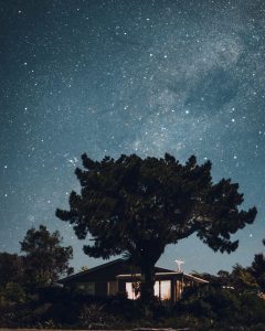 A starry nighttime shot of a house and surrounding trees