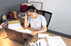medical student at desk, studying, with study notes and laptop 