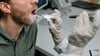 Doctor's hands using a tongue depressor and light to examine a patient's open mouth