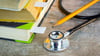 Stethoscope next to a pencil and textbooks