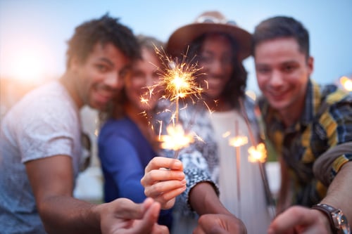 Group of friends holding sparklers at sunset