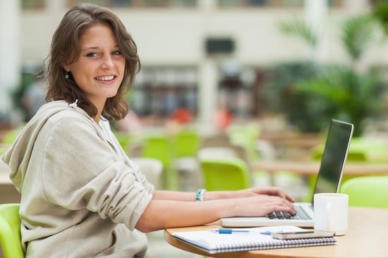 Side view portrait of a female student using laptop at cafeteria table - test