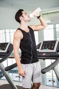 man on treadmill drinking water at the gym
