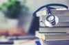 A stack of textbooks with a stethoscope on top